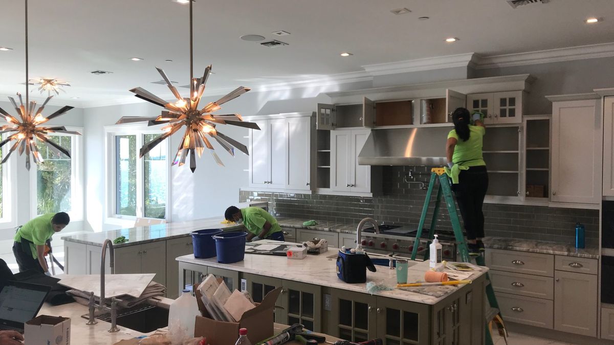 DDL Cleaning Services crew working a kitchen — cabinets, counters, and supplies on the island.